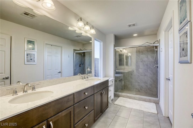 bathroom with tile patterned floors, a shower stall, double vanity, a sink, and visible vents