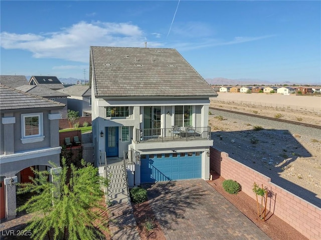 view of front of home with a residential view, stucco siding, stairs, decorative driveway, and an attached garage