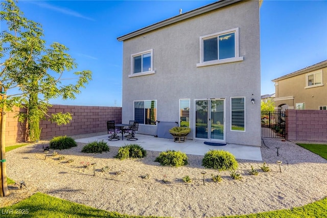 rear view of house with a fenced backyard, stucco siding, and a patio area