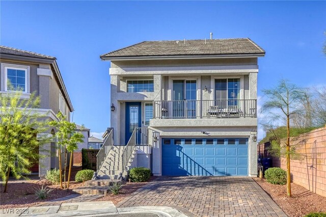 view of front of property featuring a garage, fence, stucco siding, and decorative driveway