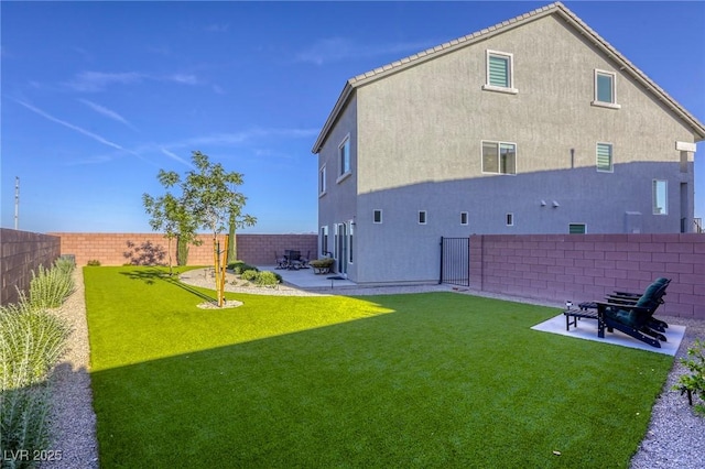 back of property with a lawn, stucco siding, a fenced backyard, and a patio area