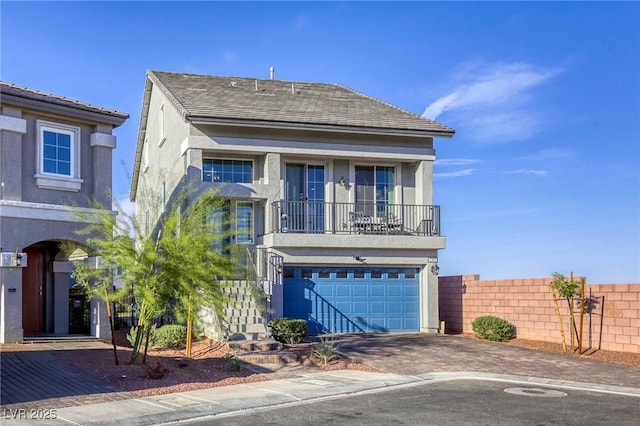 view of front of house featuring stucco siding, decorative driveway, a balcony, and a garage