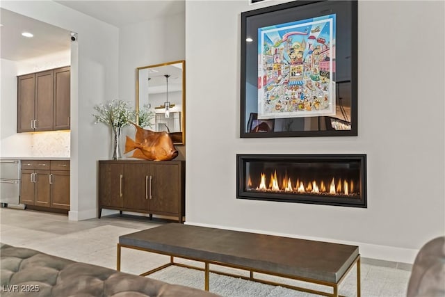 living area with baseboards, a glass covered fireplace, and recessed lighting