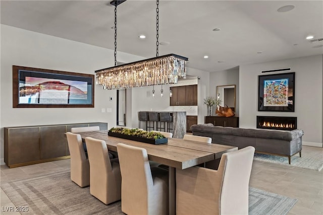 dining room with baseboards, recessed lighting, an inviting chandelier, and a lit fireplace