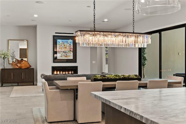 dining room featuring a chandelier, a warm lit fireplace, and recessed lighting