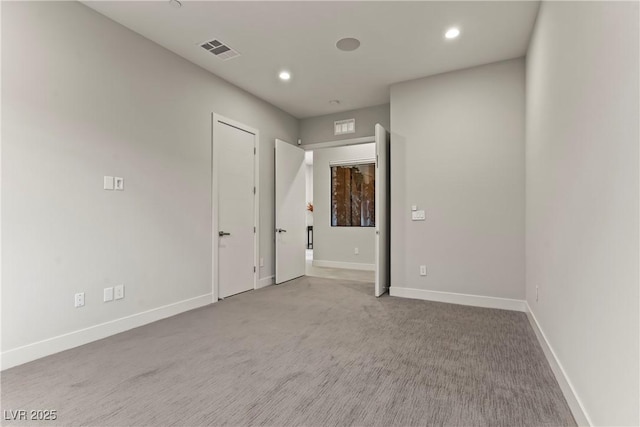 carpeted spare room featuring visible vents, baseboards, and recessed lighting