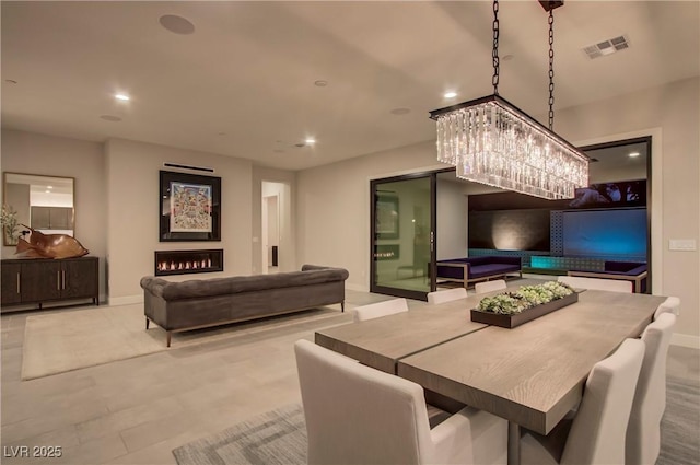 dining area with visible vents, baseboards, an inviting chandelier, a warm lit fireplace, and recessed lighting