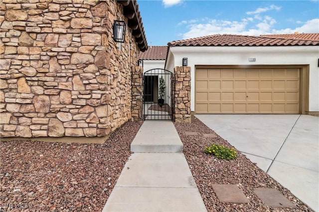 1185 Via Casa Palermo, Henderson, NV 89011 - view of exterior entry with a tile roof, a gate, driveway, stone siding, and a garage