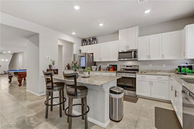 8351 Gold River Ct, Las Vegas, NV 89113 - kitchen with appliances with stainless steel finishes, light tile patterned flooring, white cabinets, a center island, and recessed lighting