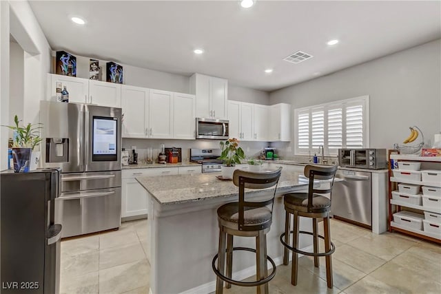8351 Gold River Ct, Las Vegas, NV 89113 - kitchen with light stone counters, white cabinetry, stainless steel appliances, and visible vents