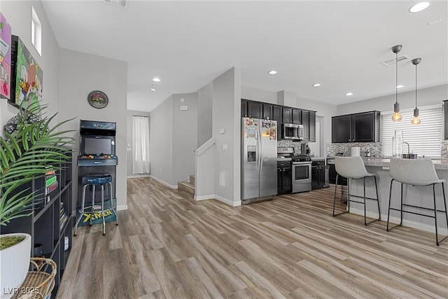 5419 Holding Ave, Las Vegas, NV 89139 - kitchen with light wood-style flooring, visible vents, appliances with stainless steel finishes, a breakfast bar area, and baseboards