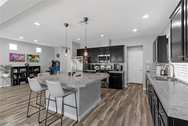 5419 Holding Ave, Las Vegas, NV 89139 - kitchen featuring backsplash, visible vents, stainless steel appliances, a sink, and wood finished floors