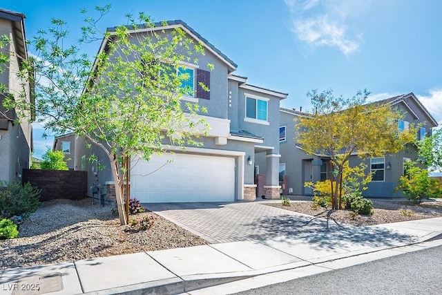 traditional-style home with decorative driveway, a garage, and stucco siding