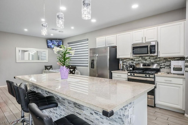 kitchen featuring white cabinets, a center island, wood finish floors, and appliances with stainless steel finishes