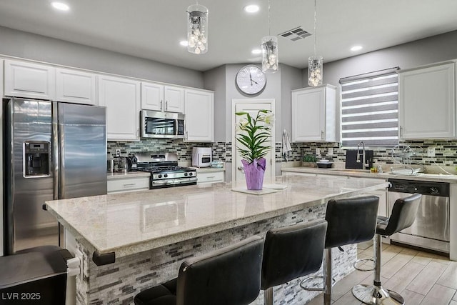 kitchen featuring tasteful backsplash, appliances with stainless steel finishes, white cabinetry, and visible vents