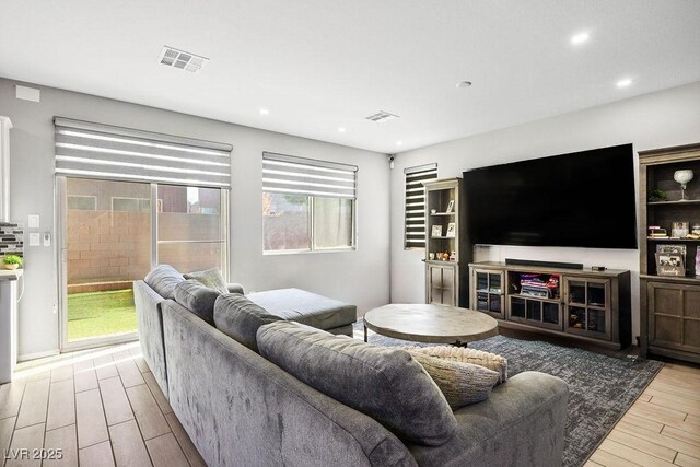 living area with wood finished floors, visible vents, and recessed lighting