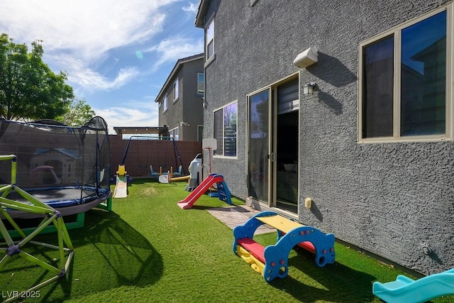 view of yard with a playground, a trampoline, and fence
