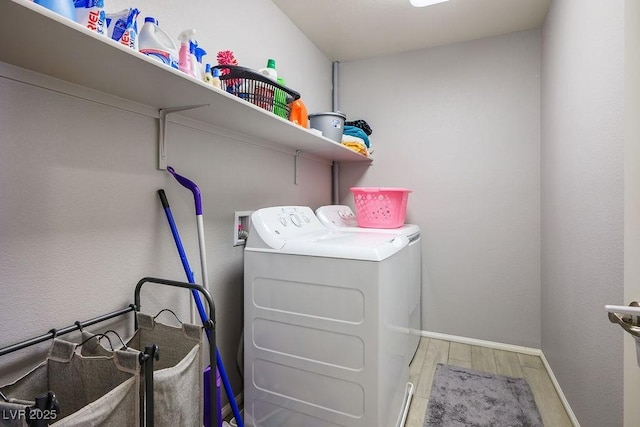 laundry area featuring laundry area, wood finished floors, baseboards, and washing machine and dryer
