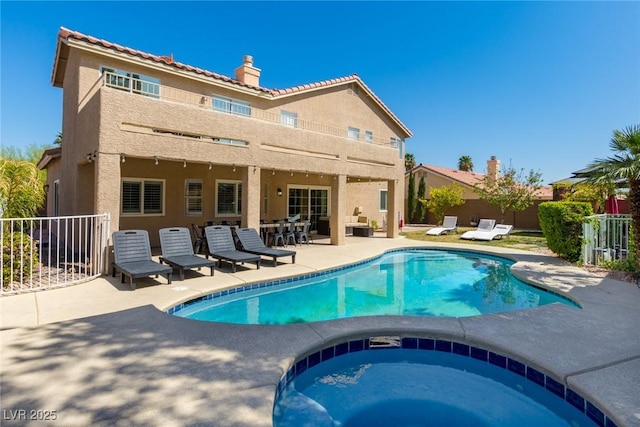 back of house with a fenced in pool, a patio, stucco siding, an in ground hot tub, and fence