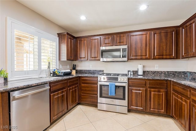 kitchen featuring a sink, recessed lighting, dark stone counters, stainless steel appliances, and light tile patterned flooring