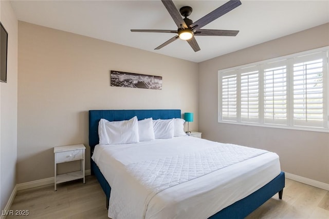 bedroom featuring baseboards, light wood finished floors, and a ceiling fan