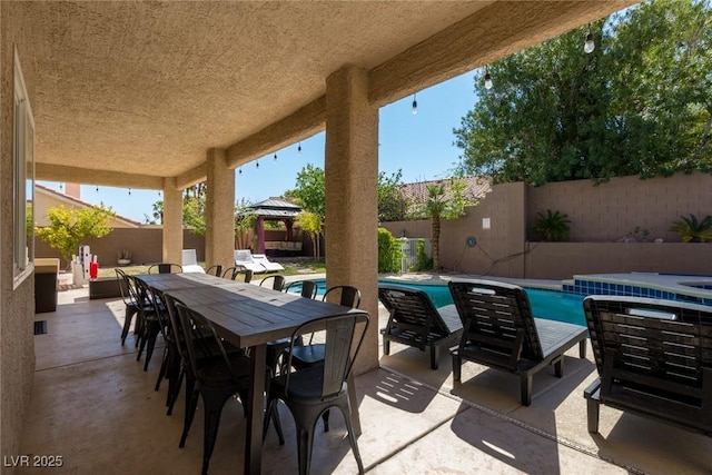 view of patio / terrace featuring a fenced backyard, outdoor dining space, a fenced in pool, and a gazebo