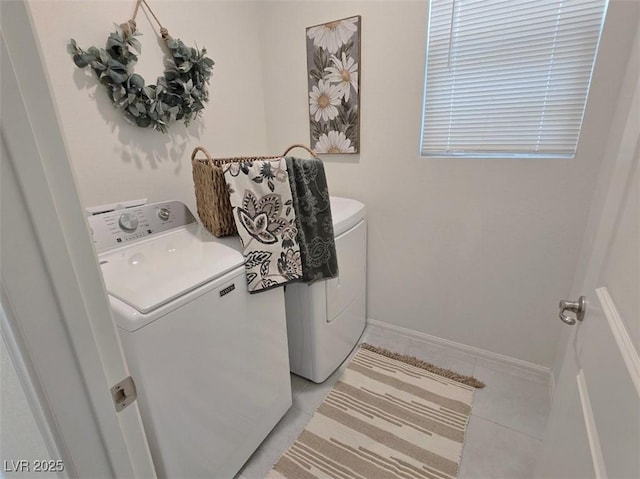 washroom with baseboards, washer and clothes dryer, light tile patterned floors, and laundry area