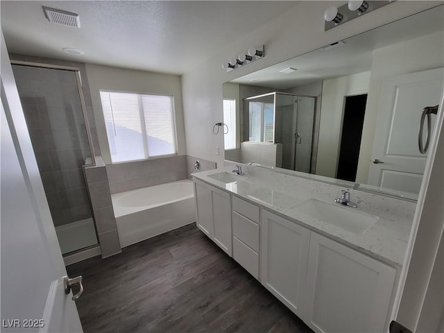 bathroom featuring a sink, a shower stall, wood finished floors, and a garden tub
