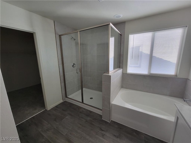 bathroom featuring a bath, a stall shower, and wood finished floors