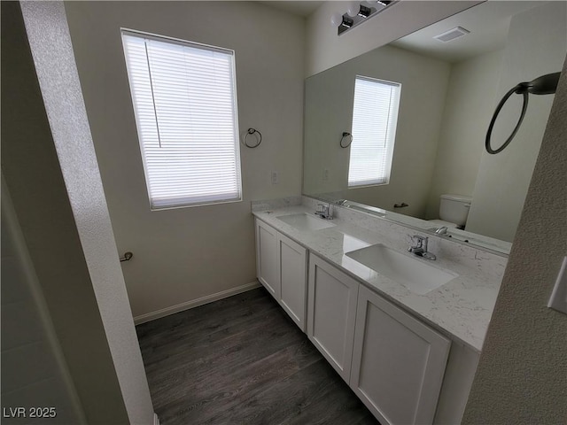 bathroom featuring a wealth of natural light, a sink, toilet, and wood finished floors