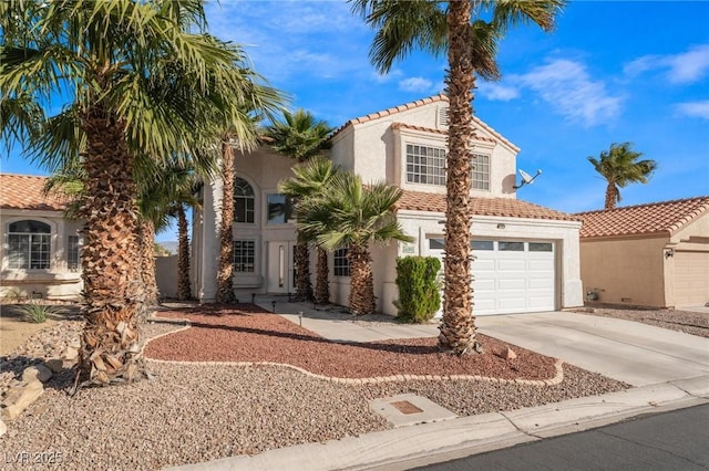 mediterranean / spanish house with a tiled roof, concrete driveway, and stucco siding