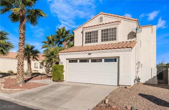 mediterranean / spanish house featuring an attached garage, driveway, stucco siding, and a tile roof