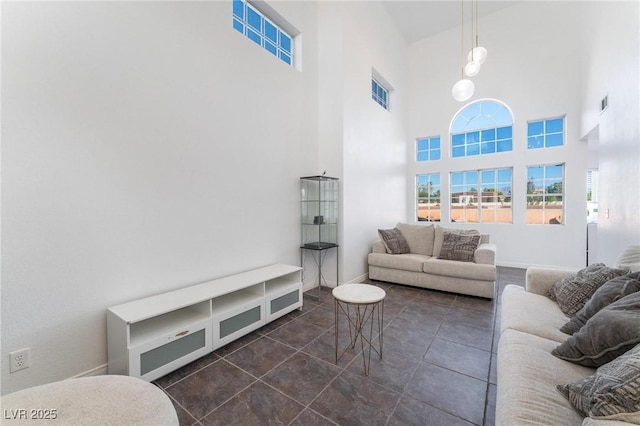 tiled living room with visible vents, baseboards, a high ceiling, and a healthy amount of sunlight