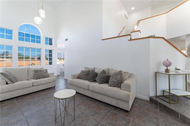living area featuring a towering ceiling, baseboards, and visible vents