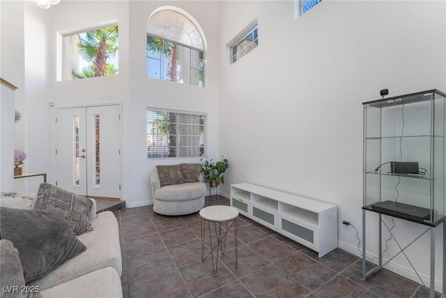 living area with baseboards and a high ceiling