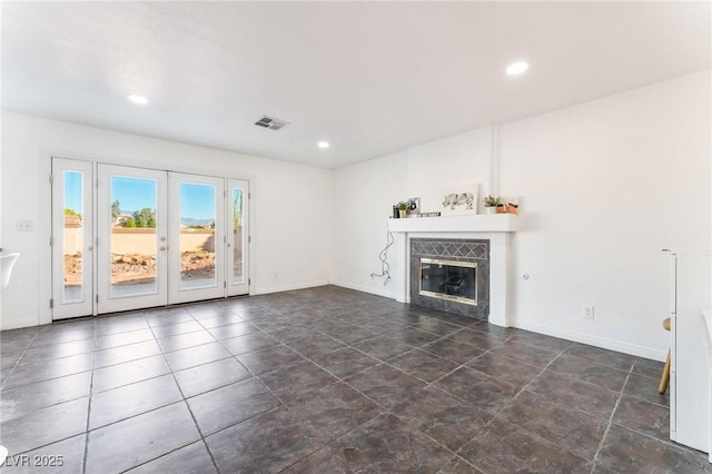 unfurnished living room featuring a tiled fireplace, visible vents, baseboards, and french doors