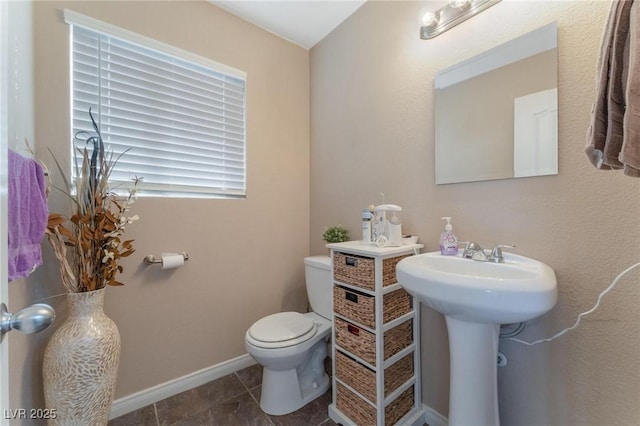 half bathroom featuring baseboards, a sink, and toilet