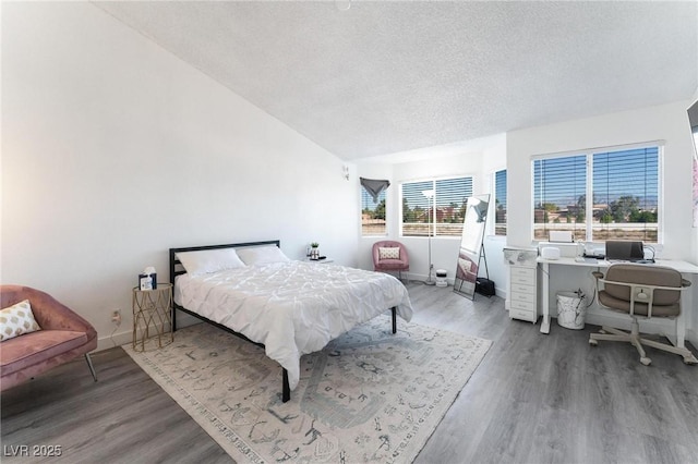 bedroom with a textured ceiling, wood finished floors, and baseboards