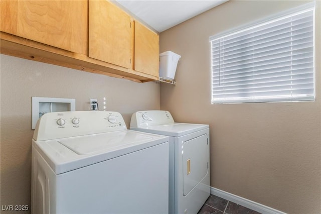 laundry area with dark tile patterned flooring, washing machine and dryer, baseboards, and cabinet space