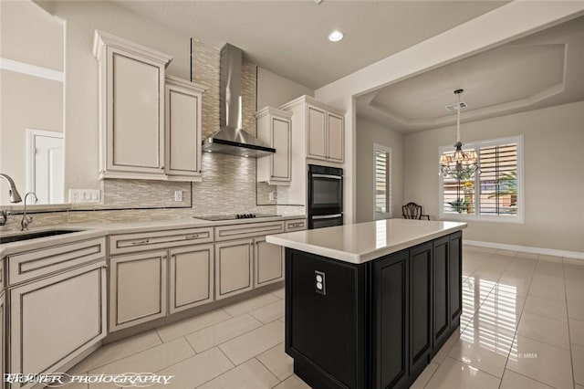 kitchen with a sink, light countertops, black appliances, and wall chimney exhaust hood