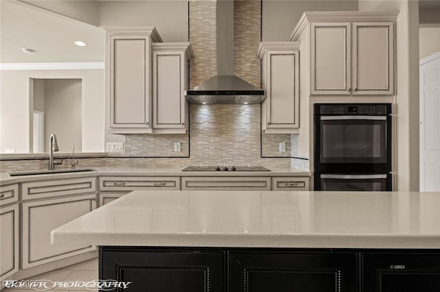 kitchen with a sink, black appliances, wall chimney exhaust hood, decorative backsplash, and light countertops