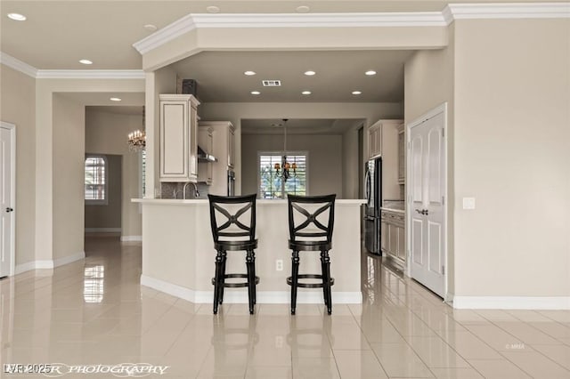 kitchen with a peninsula, an inviting chandelier, a breakfast bar, freestanding refrigerator, and light countertops