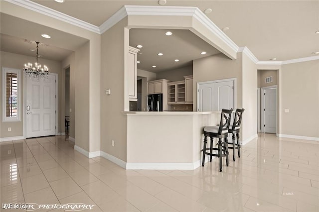 kitchen featuring black refrigerator, a chandelier, crown molding, light tile patterned floors, and baseboards