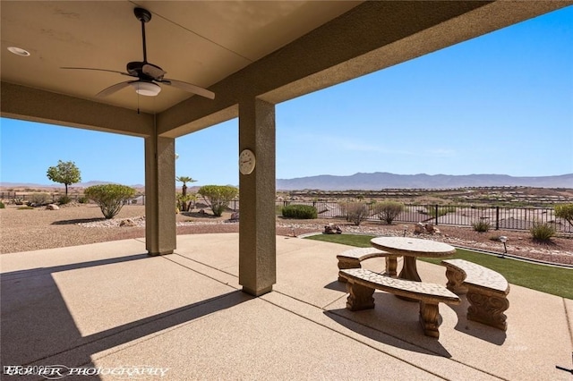 view of patio featuring a mountain view, fence, and ceiling fan