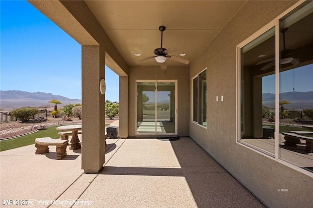 view of patio with ceiling fan and a mountain view