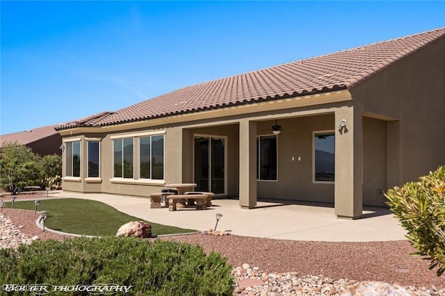 rear view of property featuring a ceiling fan, stucco siding, a tiled roof, and a patio