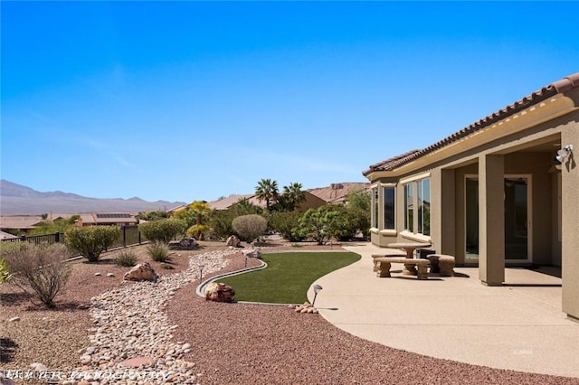 view of yard featuring a patio, a mountain view, and fence