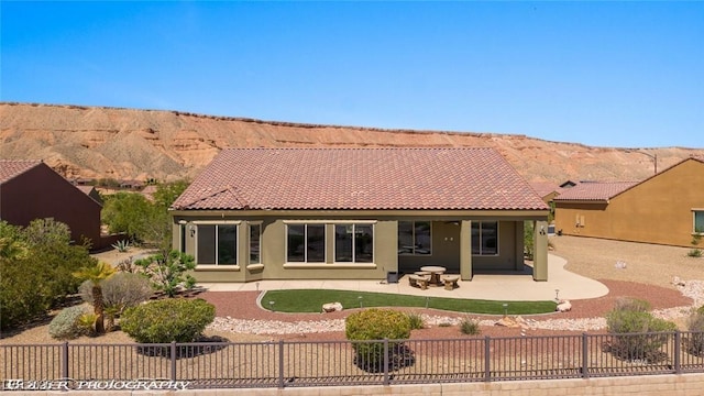 rear view of house featuring a mountain view, a patio, stucco siding, a tile roof, and a fenced backyard
