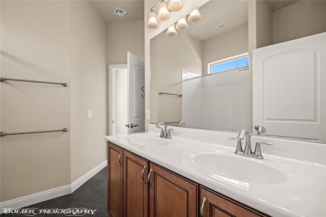 bathroom with a sink, double vanity, baseboards, and tile patterned floors