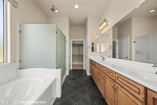 bathroom with a walk in closet, tile patterned floors, a stall shower, double vanity, and a bath